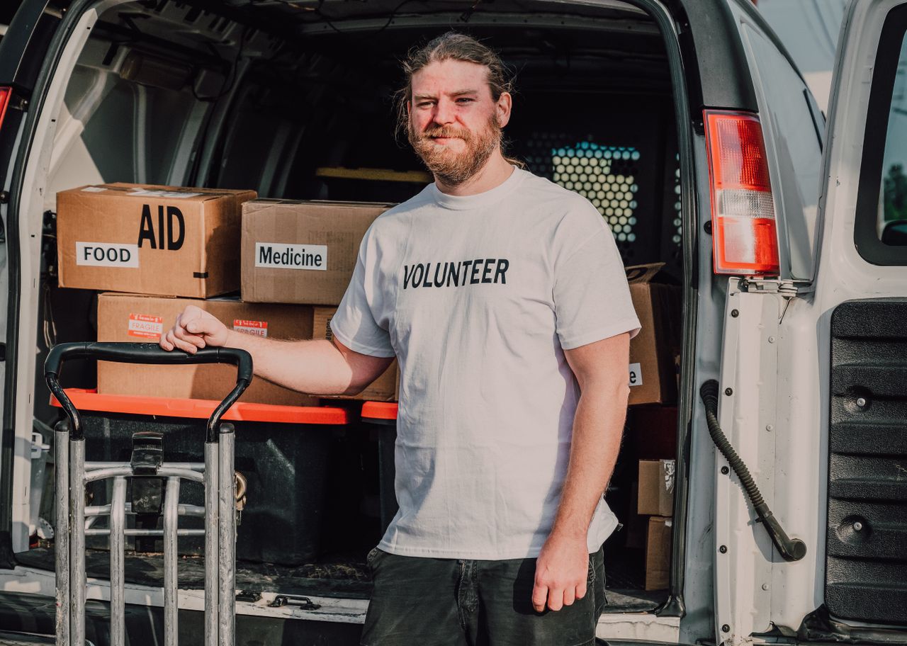 services-03 Volunteer standing by a van loaded with aid supplies, ready to serve the community.
