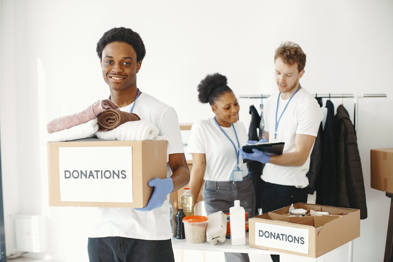 services-02 Diverse group of volunteers organizing donation boxes with clothes and supplies indoors.